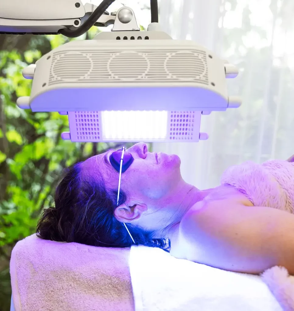 Lady receiving an LED facial with blue lights.